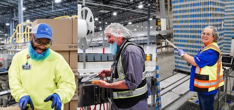 Three warehouse workers in safety gear discuss operations in an industrial facility with machinery and storage in the background.