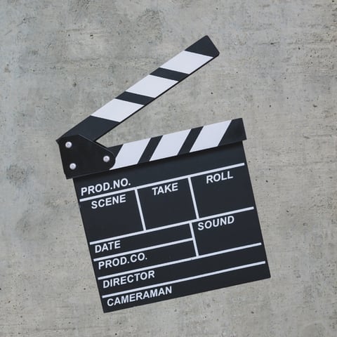 Black and white film clapperboard resting on concrete surface with labeled fields for production details