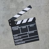 Black and white film clapperboard with striped top placed on concrete surface